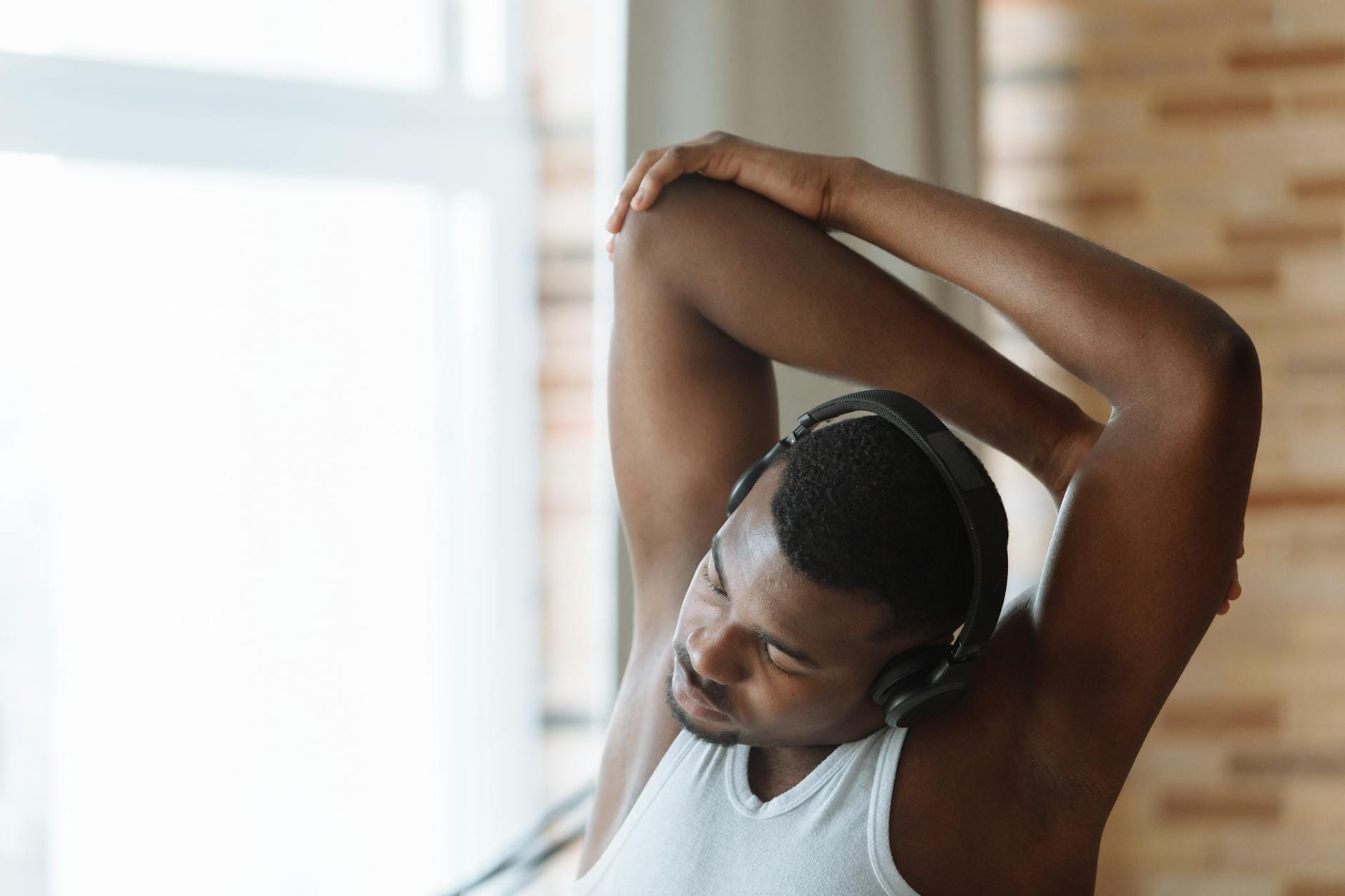 Mężczyzna w białej koszulce rozciąga się w warsztacie w słuchawkach
