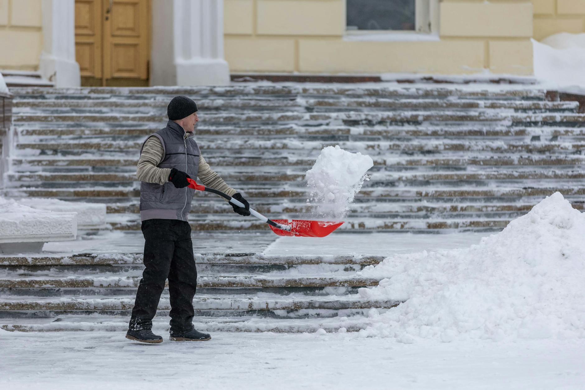 Mężczyzna odgarnia śnieg z zewnętrznych schodów podczas zamieci