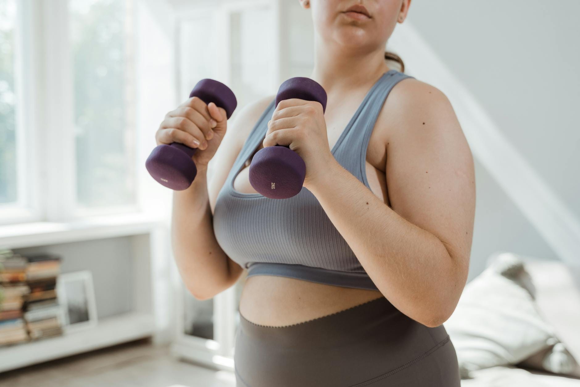 Kobieta plus size ćwiczy w domu z hantlami zamiast biegać