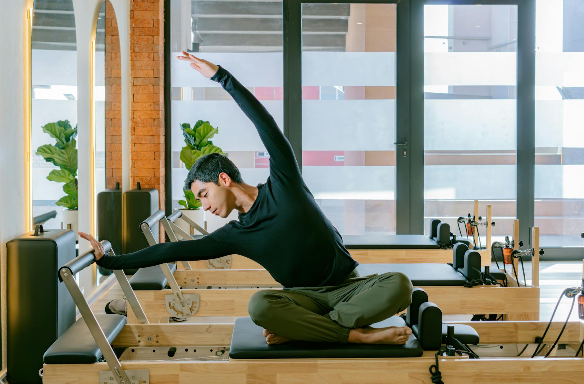 Mężczyzna ćwiczy kręgosłup na reformerze Pilates w jasnym studiu