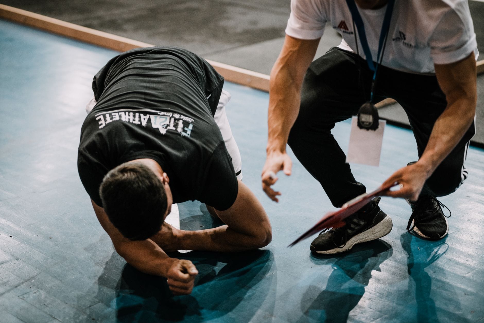 Jak mierzyć postęp bez biegania: testy kondycji w domu i w pracy Zawodnik wykonuje test sprawności pod okiem trenera na sali sportowej
