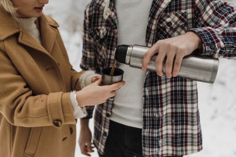 Para nalewa gorącą kawę z termosu podczas zimowego wypadu w śniegu